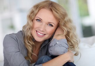 blond woman smiling leaning on elbow, Fond du Lac, WI dental crowns and bridges