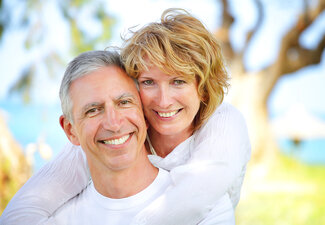 mature couple smiling outdoors near lake, dental implants Fond du Lac, WI